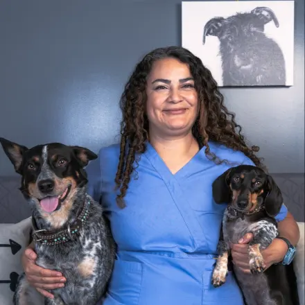 Dr. Sanzhez smiling and holding two dogs by her side